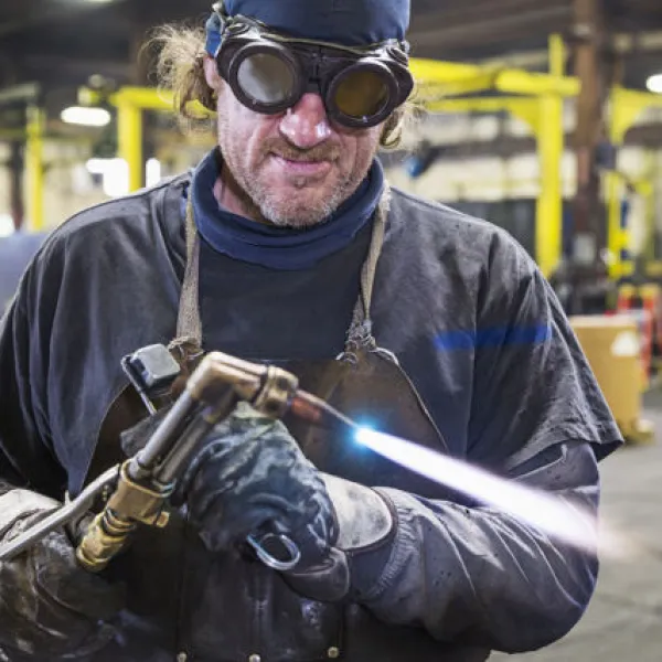 Soudeur réglant un chalumeau dans une usine